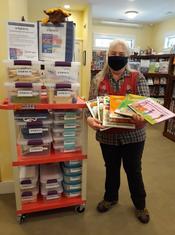 Assistant Librarian Lynn Ufer standing with STEM Kits display