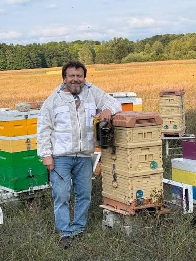 Beekeeper Rick Dimanin standing beside his beehives.